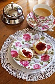 Scones on saucer with rose designs, tea cup and saucer on wooden table