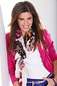 Portrait of beautiful woman with dark hair in pink jacket and colourful scarf, smiling