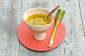 Whey soup in bowl with spring onions on plate