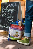 Woman leg near shopping bag and display board in Lindener market, Hannover, Germany