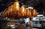 Chef in kitchen with hanging roasted goose in Yung Kee Restaurant, Hong Kong
