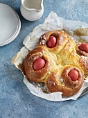 Greek Easter bread with red eggs on baking paper