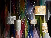 Various illuminated ceiling lamps in front of geometric non woven wallpaper