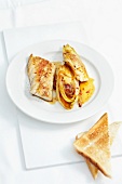 Pollock fillets with chicory on plate and bread slices on platter