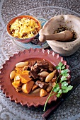 Beef tagine with figs on plate, bowl of pasta with raisins and mortar