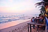 People sitting in bar at Hikkaduwa beach during sunset, Sri Lanka