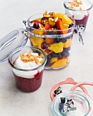 Fruit salad with candied pine nuts and raspberry compote in glass containers