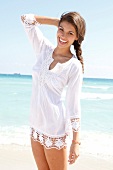 Dark-haired woman in a white blouse laughing by the sea