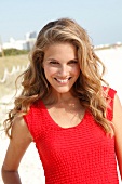 blonde Frau im roten Top am Strand, lacht im Kamera