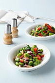 Two bowl of broad bean salad with salt and pepper shakers