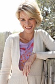 Portrait of pretty blonde woman with short hair wearing top and white cardigan, smiling