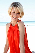 blonde Frau trägt Top, orange, am Strand