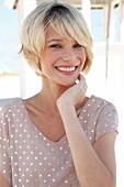 Portrait of happy blonde woman with short hair wearing polka dots dress, smiling