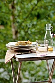 Landküche, ein Stück Kuchen + Glas mit Getränk auf Gartentisch