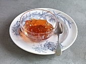 Jelly jam in bowl with spoon on plate