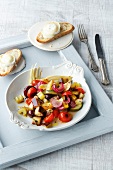 Dish of oven roasted ratatouille with bread slices on square tray