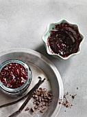 Cherry jam in jar with chocolate chips on plate