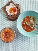 Apricot jam and peach jam in bowls and two slices of bread