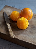 Close-up of whole and peeled oranges on chopping board with knife, marmalade