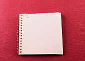 weißes Ringbuch mit Büroklammer, roter Hintergrund