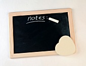 Slate blackboard with note written by chalk and sponge heart for erasing