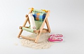 Rolled-up currency on small deck chair with flip-flops and sand