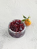 Currant jelly with kumquats in glass jar and whole kumquat on white background