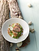 Plate of involtini with parma ham, pea risotto and quail eggs on wood log