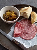 Orange and olive jam, salami and bread on wooden board