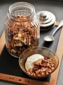 Autumn cereal with maple syrup and nuts in glass bowl and jar