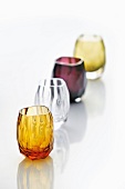 Close-up of different colour shot glasses for vodka against white background