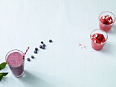 Glasses of blueberry smoothie and raspberry sorbet on white background