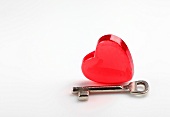 Close-up of heart shaped glass with key on white background