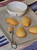 Orange madeleines, brush and dressing in bowl in baking dish