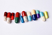 Various coloured capsules arranged in a row on white background