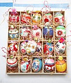 Colourfully painted Easter eggs in a seedling tray lined with straw