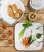 Snacks with dips and vegetables and rolls, overhead view