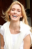 Portrait of beautiful blonde woman with long hair wearing white sweater, smiling