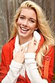 Portrait of beautiful blonde woman with long hair in white and orange cardigan, smiling