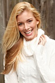 Portrait of beautiful blonde woman with long hair in white turtleneck sweater, smiling