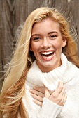 Portrait of beautiful blonde woman with long hair in white turtleneck sweater, smiling