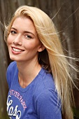 Portrait of attractive blonde woman with long hair wearing blue top, smiling