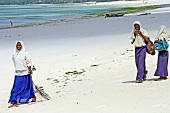 Three girls in uniform walking on beach of Zanzibar, Tanzania, East Africa