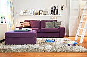 Living room with purple sofa, pouf, ladder and picture frames on wall