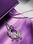 Halskette auf lilafarbenem Hinter- grund