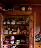 View of wooden cupboard with colorful bowls, dishes and plates