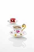 Gold plated coffee cup and saucer with rose pattern on white background