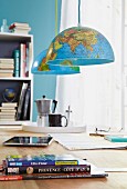 Two halves of a globe as pendant lamps hanging over a table