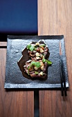 Bark fillet tataki with shiitake mushrooms, macadamia nuts and watercress leaves on plate