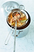 Bouillabaisse with lobster soup in strainer over pot
